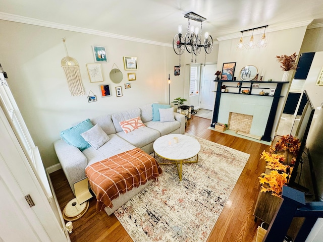 living room featuring baseboards, ornamental molding, wood finished floors, and a notable chandelier