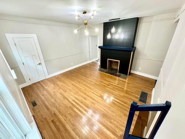 unfurnished living room with a large fireplace, visible vents, baseboards, and light wood finished floors