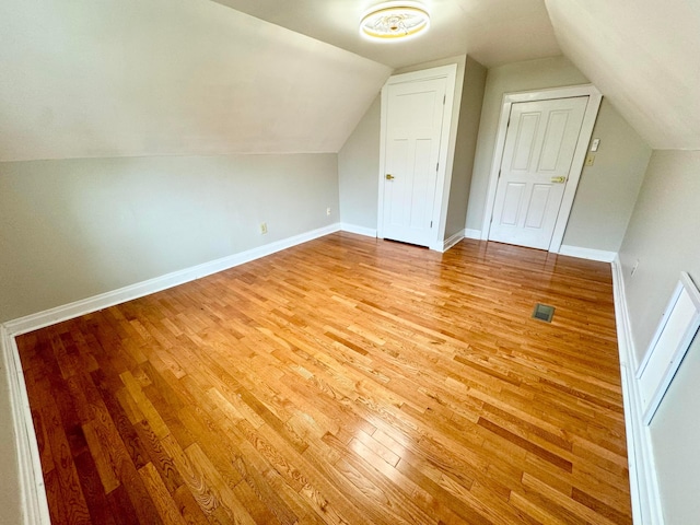 bonus room featuring lofted ceiling, light wood-style flooring, visible vents, and baseboards