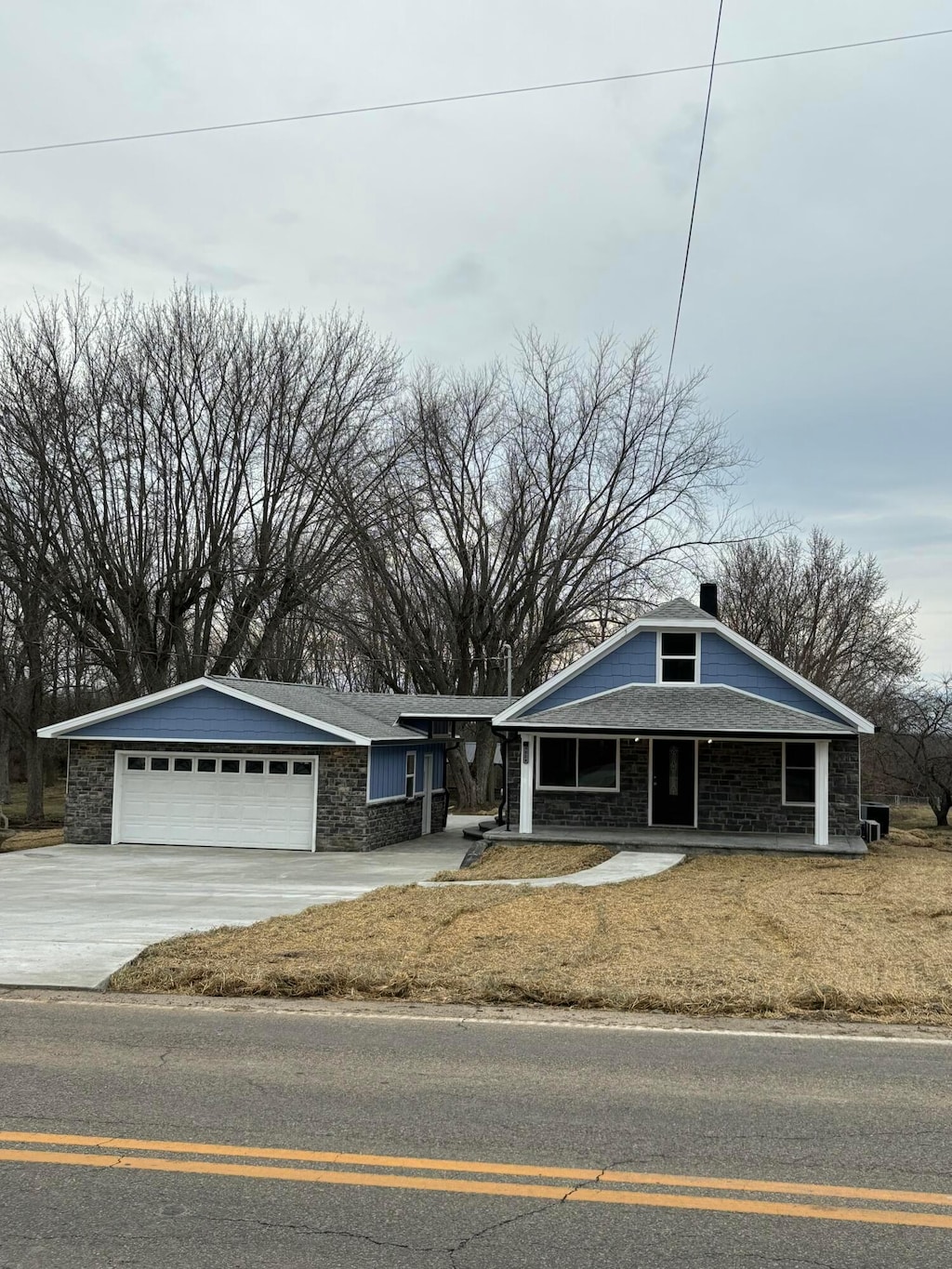 view of front of property with a garage, driveway, a chimney, and stone siding