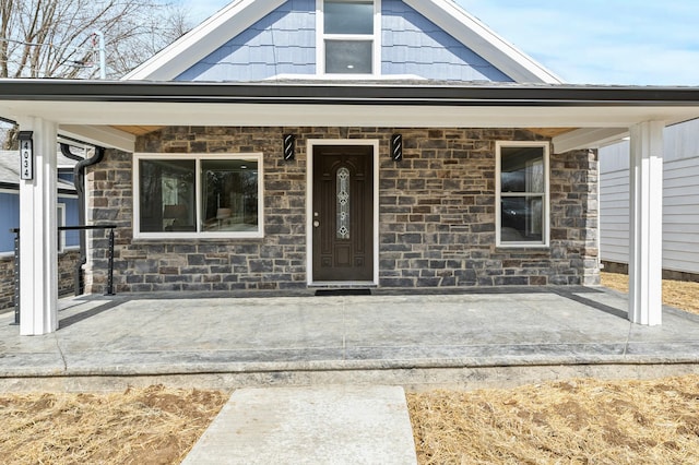 entrance to property featuring stone siding and a porch