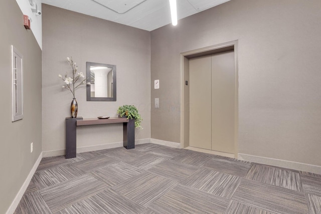 carpeted entrance foyer featuring elevator and baseboards