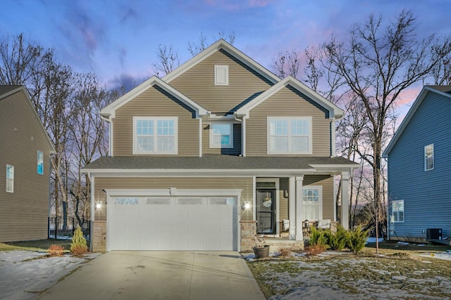 view of front of house featuring central air condition unit, concrete driveway, covered porch, an attached garage, and stone siding