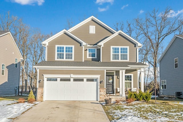 traditional-style home with a garage, central AC unit, concrete driveway, stone siding, and covered porch