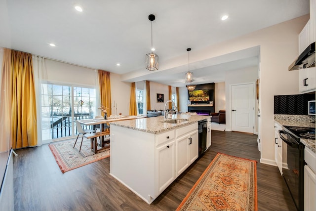 kitchen featuring light stone counters, dark wood-style floors, open floor plan, a sink, and black appliances