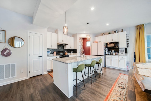 kitchen with under cabinet range hood, dark wood-type flooring, visible vents, white cabinets, and black appliances