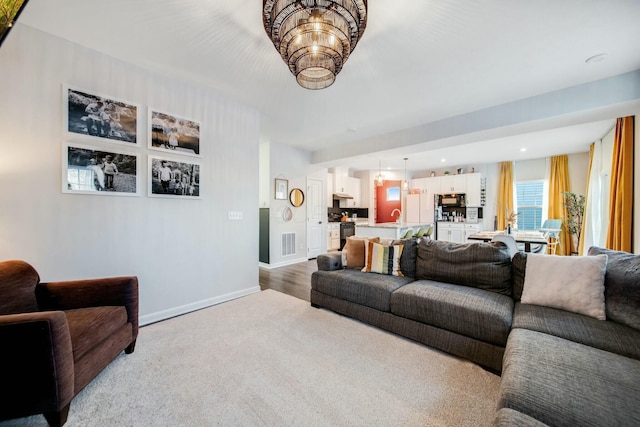 carpeted living area with recessed lighting, visible vents, an inviting chandelier, a sink, and baseboards