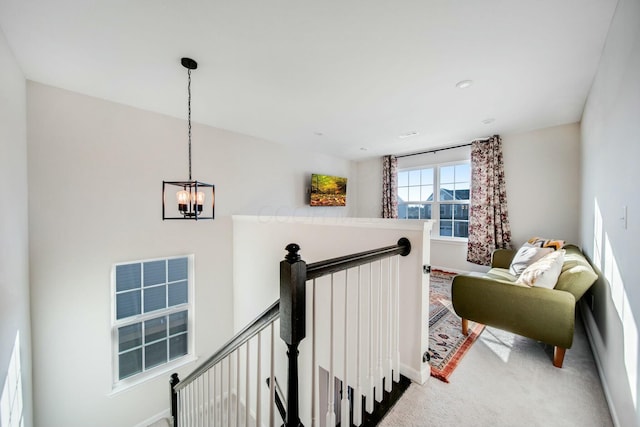 interior space featuring baseboards, carpet flooring, a notable chandelier, and an upstairs landing