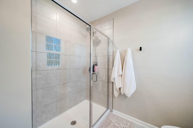 full bathroom featuring a shower stall and baseboards