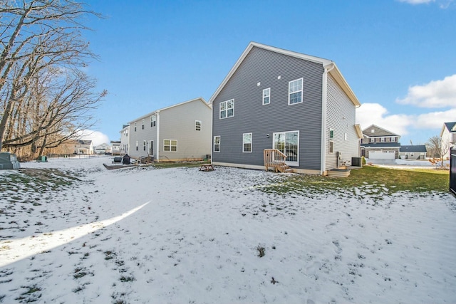 snow covered rear of property featuring central AC