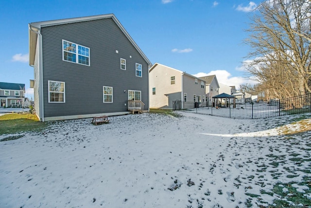 snow covered rear of property featuring a residential view and fence