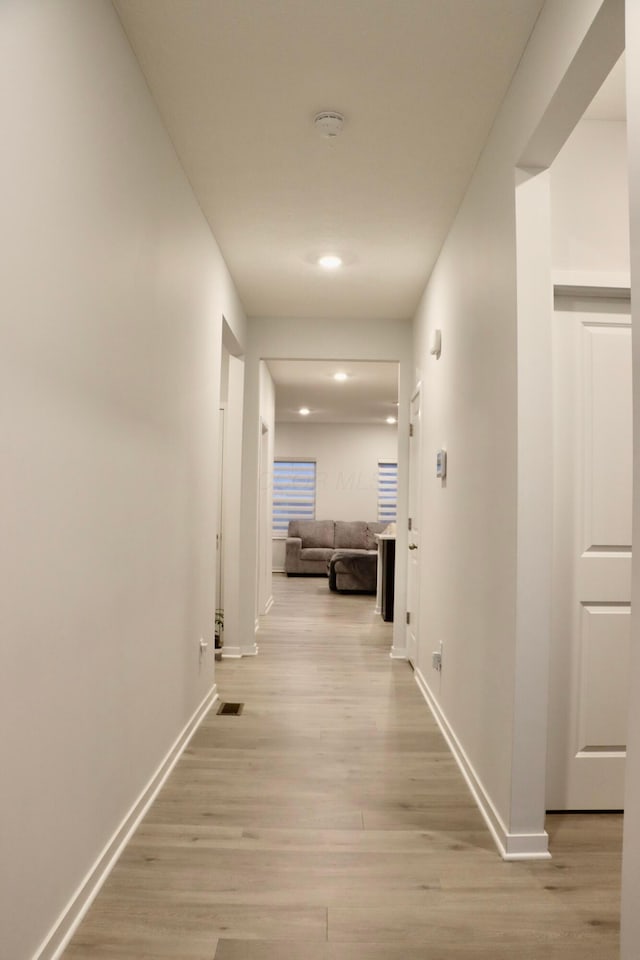 hallway featuring light wood finished floors, recessed lighting, visible vents, and baseboards