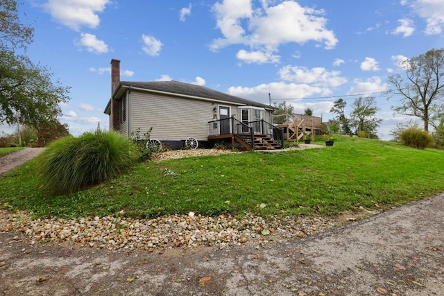 view of side of home featuring a chimney, a lawn, stairway, and a wooden deck