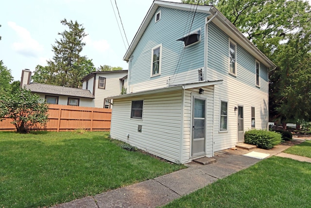 rear view of property with a lawn and fence