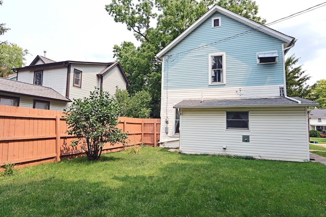 rear view of house featuring fence and a yard