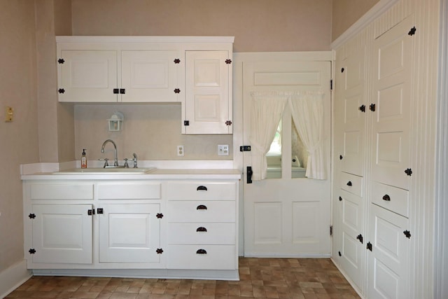 kitchen with white cabinetry, light countertops, and a sink