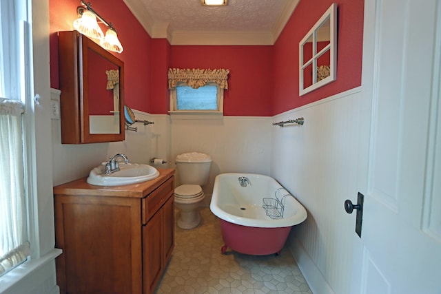 full bathroom with wainscoting, toilet, a soaking tub, a textured ceiling, and vanity