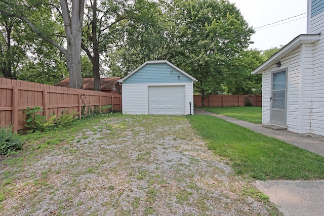 view of yard featuring a garage, driveway, an outbuilding, and a fenced backyard