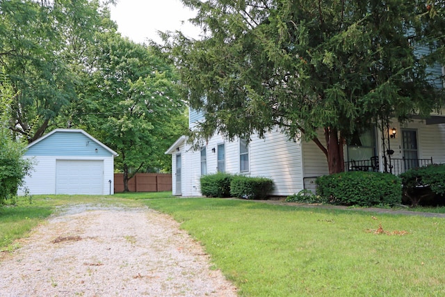 view of side of home featuring an outbuilding, a porch, a garage, driveway, and a yard