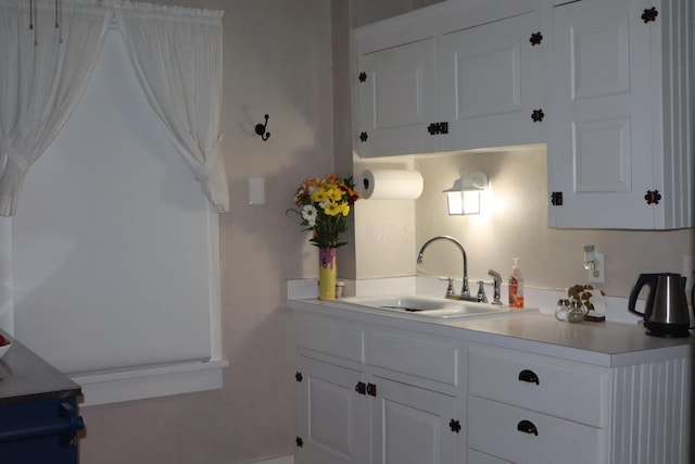 kitchen with white cabinets, light countertops, and a sink