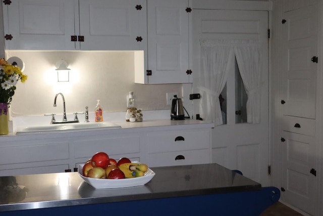 kitchen featuring white cabinetry, light countertops, and a sink