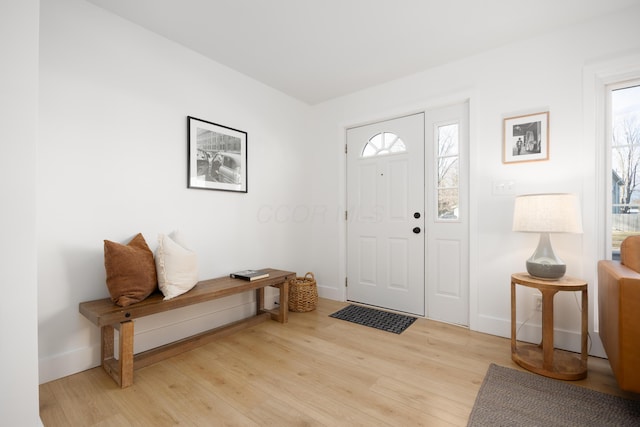 entryway with baseboards, plenty of natural light, and light wood-style floors