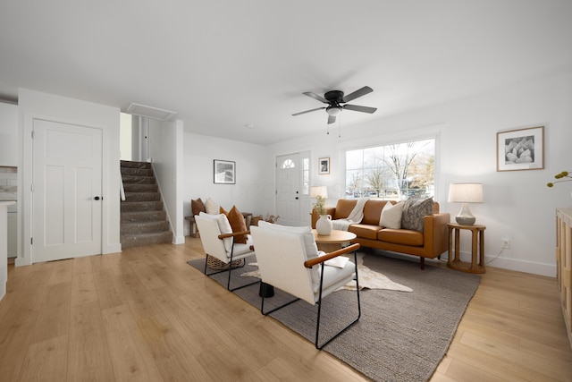 living area with ceiling fan, baseboards, stairway, light wood-type flooring, and attic access