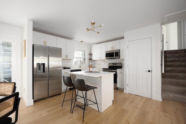 kitchen with appliances with stainless steel finishes, light wood-style floors, white cabinetry, and tasteful backsplash