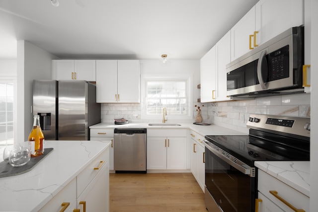 kitchen featuring stainless steel appliances, a sink, white cabinets, and light wood-style floors