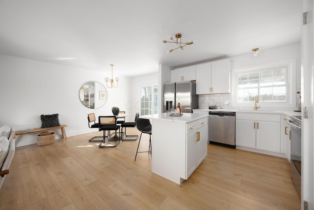 kitchen featuring light wood finished floors, a kitchen island, appliances with stainless steel finishes, and a sink