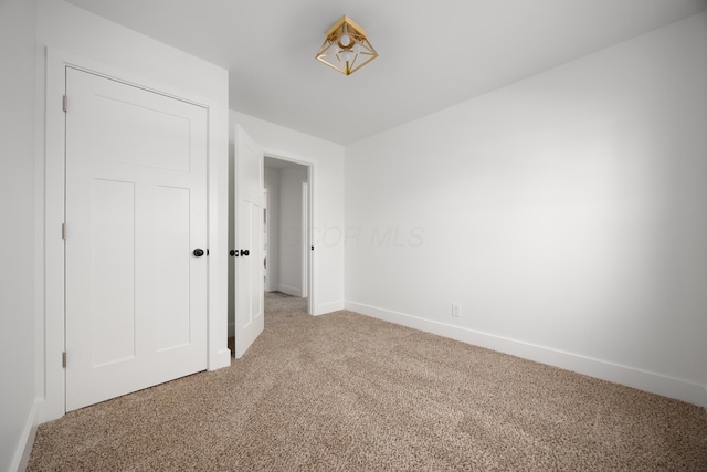 spare room with light carpet and baseboards