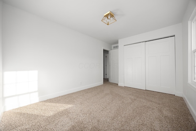 unfurnished bedroom with baseboards, carpet, visible vents, and a closet