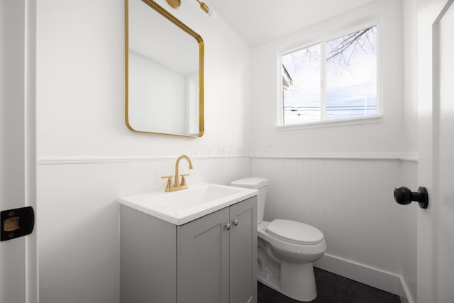 half bath featuring toilet, wainscoting, and vanity