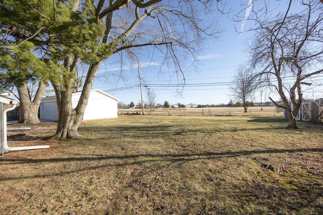 view of yard featuring an outbuilding, fence, and a garage