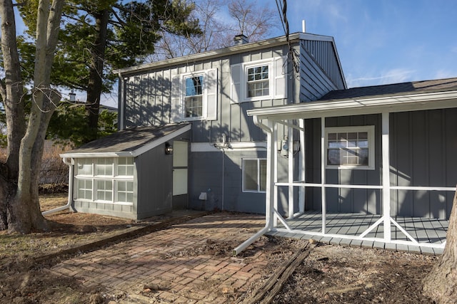 rear view of house featuring board and batten siding, a sunroom, and a patio