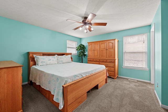 bedroom featuring a ceiling fan, light carpet, a textured ceiling, and baseboards