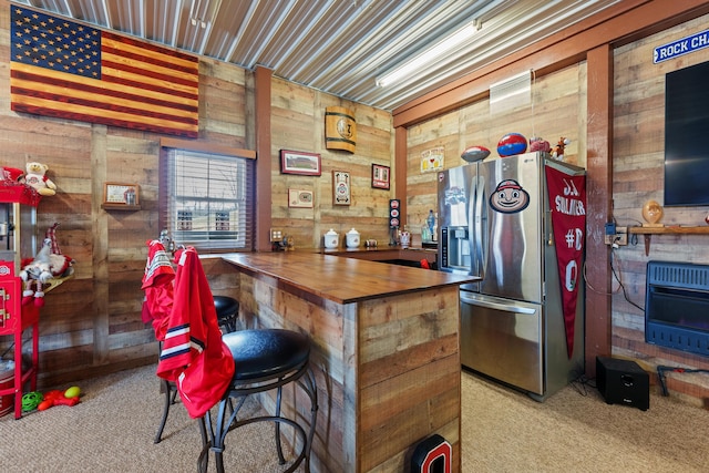 interior space with carpet floors, heating unit, wooden walls, a bar, and stainless steel fridge