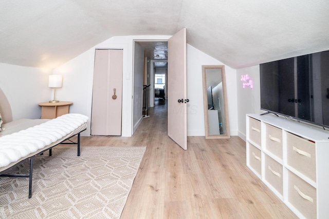 bedroom featuring light wood-style floors, lofted ceiling, and baseboards