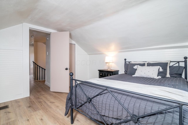 bedroom with vaulted ceiling, wood finished floors, and visible vents