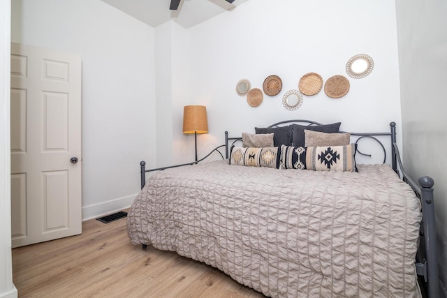 bedroom featuring a ceiling fan, visible vents, baseboards, and wood finished floors