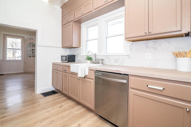 kitchen with light countertops, stainless steel dishwasher, plenty of natural light, and a sink