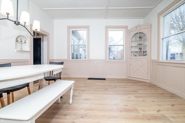 dining room with a wainscoted wall, light wood-type flooring, and visible vents