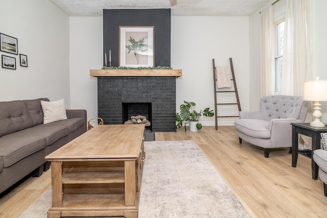 living room with a brick fireplace, baseboards, and wood finished floors