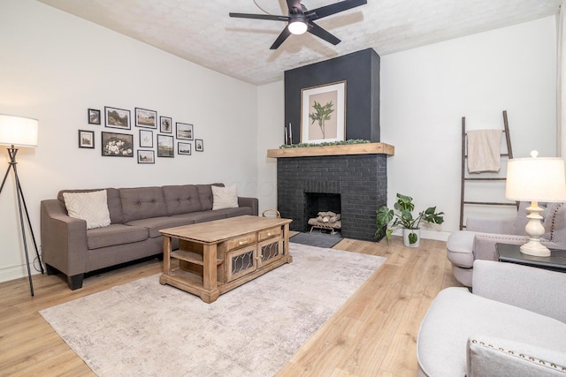 living room with a textured ceiling, a fireplace, wood finished floors, a ceiling fan, and baseboards