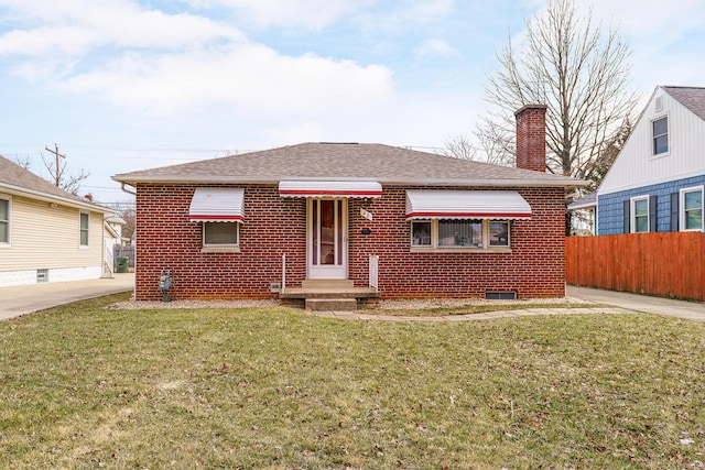 bungalow with brick siding, fence, roof with shingles, a chimney, and a front yard