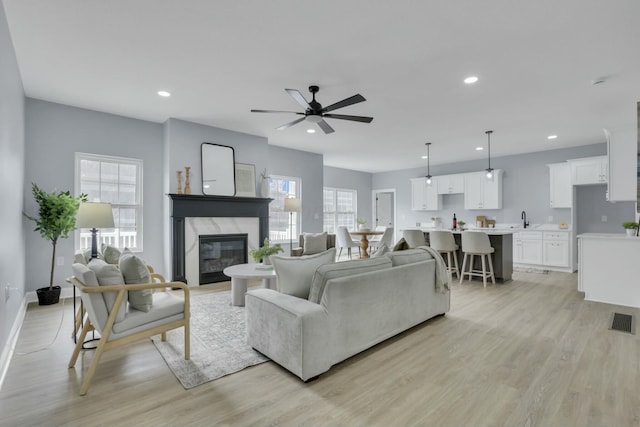 living area with light wood-type flooring, a fireplace, visible vents, and recessed lighting