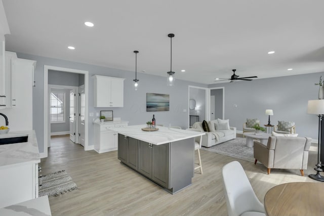 kitchen featuring light wood-style flooring, a kitchen island, white cabinetry, and recessed lighting