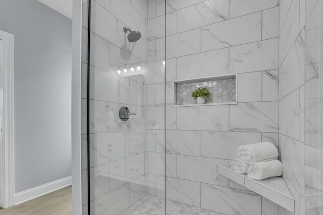 full bath featuring wood finished floors, walk in shower, and baseboards