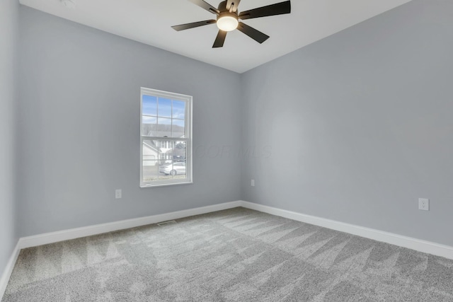 carpeted empty room with ceiling fan and baseboards