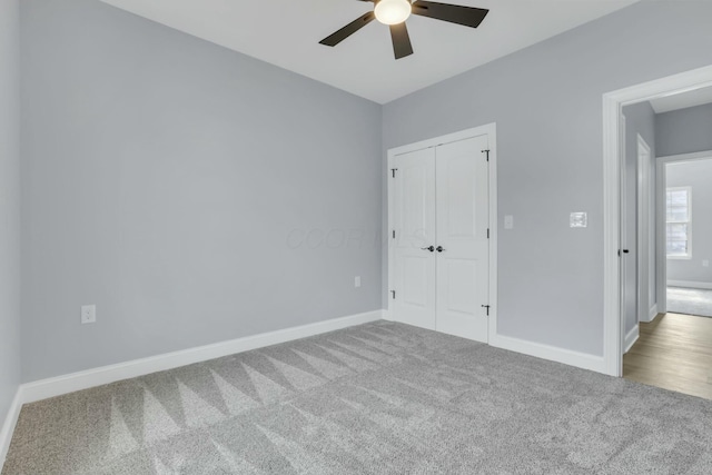 unfurnished bedroom featuring carpet floors, a closet, baseboards, and a ceiling fan